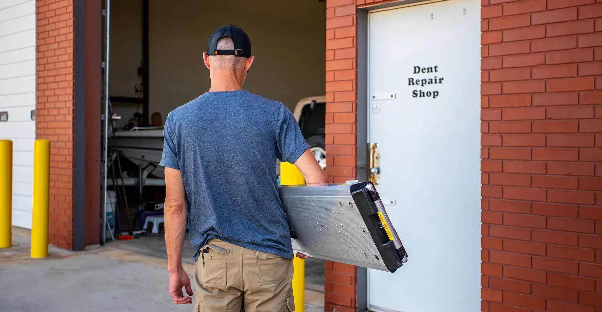 Man carrying Kwik Bench into dent repair shop